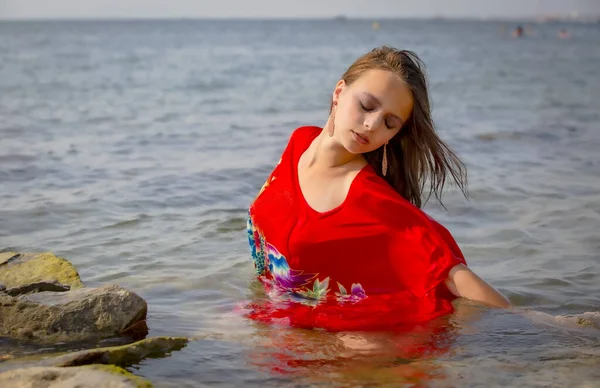 Chica Morena Mojada Vestido Rojo Sentada Agua Playa Atardecer Concepto — Foto de Stock