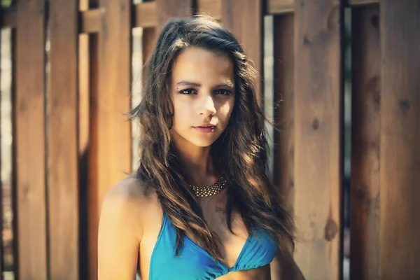 一个身穿蓝色泳衣的年轻漂亮姑娘靠在木栅栏上的画像 — 图库照片