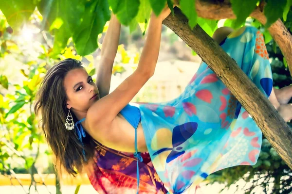 像猴子一样挂在树上的少女 长头发挂在树枝上的布鲁内特 在温暖的夏日穿着泳衣的年轻貌美的姑娘 在炎热的国家旅行 — 图库照片