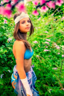 Yeşil çimlerin ve ormanın arka planında mayo giymiş manken görünümlü bir kız..