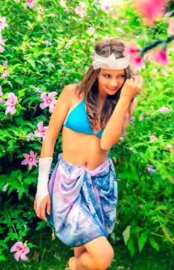 Yeşil çimlerin ve ormanın arka planında mayo giymiş manken görünümlü bir kız..