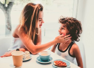 7 yaşındaki erkek kardeşini öpen ablasının bir yaz kafesinde otururken çekilmiş fotoğrafı.