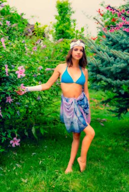 Yeşil çimlerin ve ormanın arka planında mayo giymiş manken görünümlü bir kız..