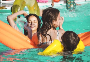 Arkadaşlar yüzme havuzunda havuz yatağıyla eğleniyor.