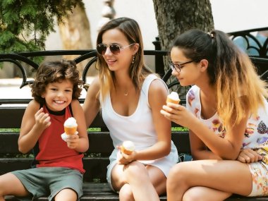 Bir yaz parkında dondurma yiyen mutlu bir aile. Kız kardeşler ve erkek kardeşler eğlenin. Yeşil parkta yürü.