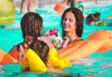 Arkadaşlar yüzme havuzunda havuz yatağıyla eğleniyor.