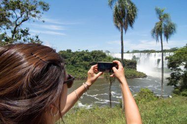 Arka planda San Martin Adası ve Iguazu Şelaleleri 'nin fotoğrafını çeken kadın.