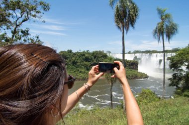 Woman Taking Photo of San Martin Island and Iguazu Falls on background clipart