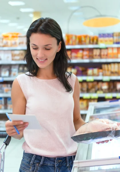 Женщина проверяет свой список покупок в супермаркете — стоковое фото