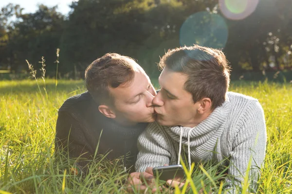  Genç gey çift birbirlerine çim üzerinde yalan öpüşme