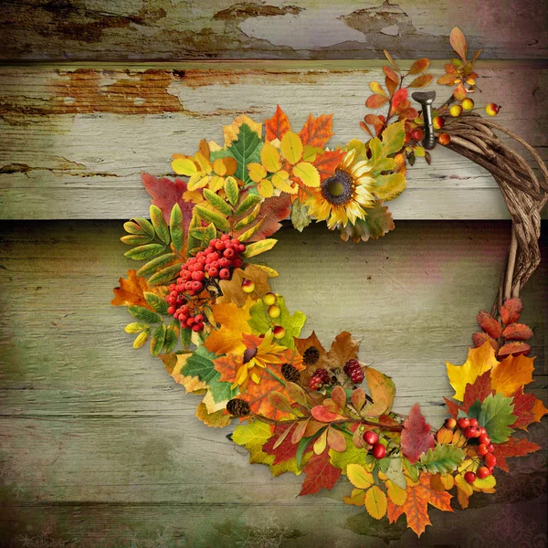 Венок осенних листьев и ягод в форме сердца на деревянном фоне — стоковое фото