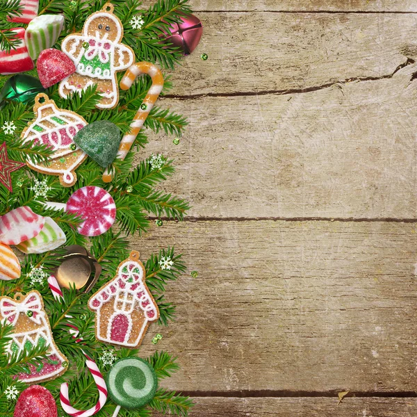 Weihnachtsplätzchen, Bonbons, Tannenzweige auf Holzgrund — Stockfoto