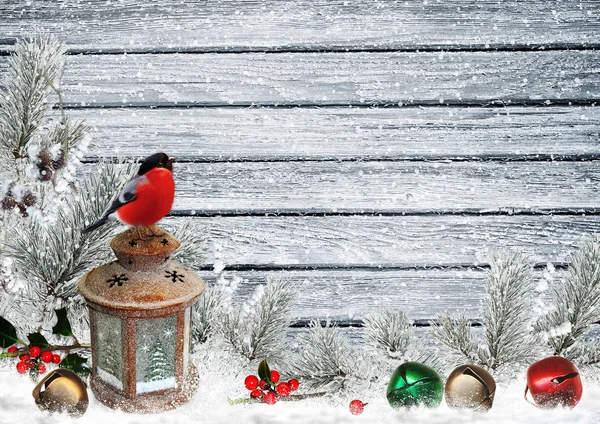 Christmas greeting card with Cristmas bells, bullfinch, lantern, pine branches on a snowy wooden board Royalty Free Stock Images