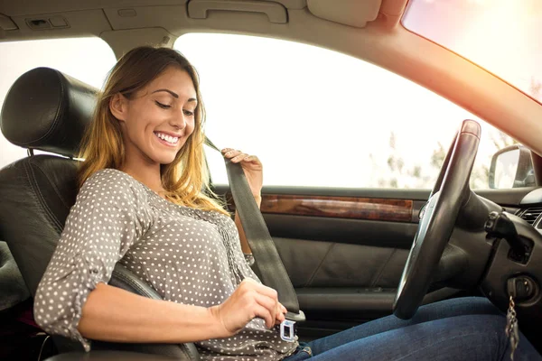 Beautiful woman putting on seatbelt — Stock Photo, Image