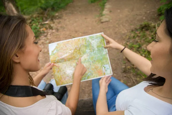 Två unga flickor tittar på en karta i skogen — Stockfoto