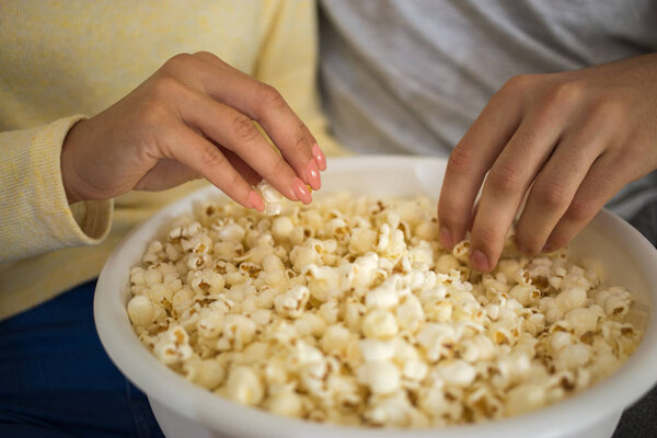 Крупный план пары, которая ест попкорн только руками

