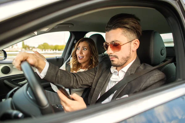 Belo casal dirigindo no carro enquanto mensagens de texto — Fotografia de Stock