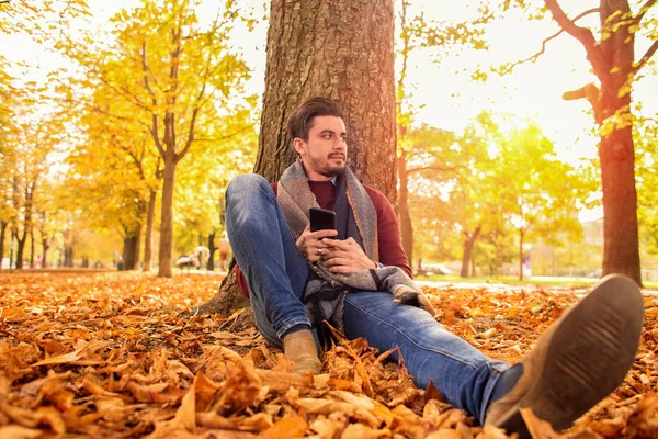Yakışıklı adam parkta sonbaharda bir mola — Stok fotoğraf