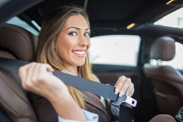 Beautiful woman putting on seatbelt — Stock Photo, Image