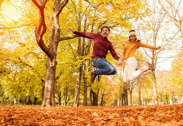 幸せなカップルの秋の公園でジャンプ — ストック写真