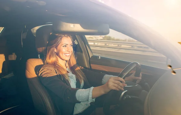 Beautiful businesswoman driving car at sunset — Stock Photo, Image