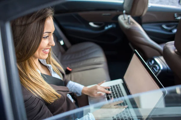 Beautiful business woman working on laptop in a limousine — Stock Photo, Image