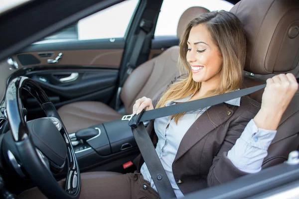 Beautiful businesswoman putting on seatbelt in car — Stock Photo, Image