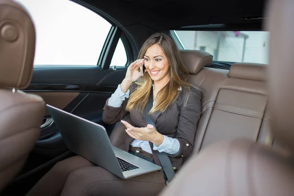 Beautiful business woman working on laptop in a limousine — Stock Photo, Image