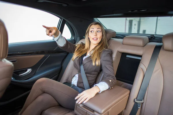 Beautiful businesswoman pointing in limousine where she wants to — Stock Photo, Image