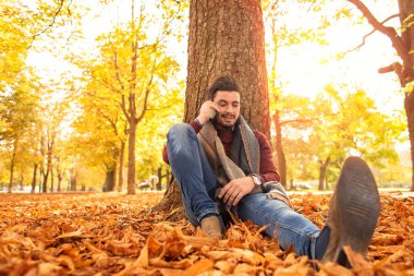 Parkta telefonda konuşan sonbaharda yakışıklı adam