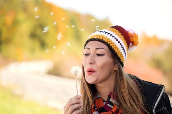 Mooie jonge vrouw paardebloem buiten blazen — Stockfoto