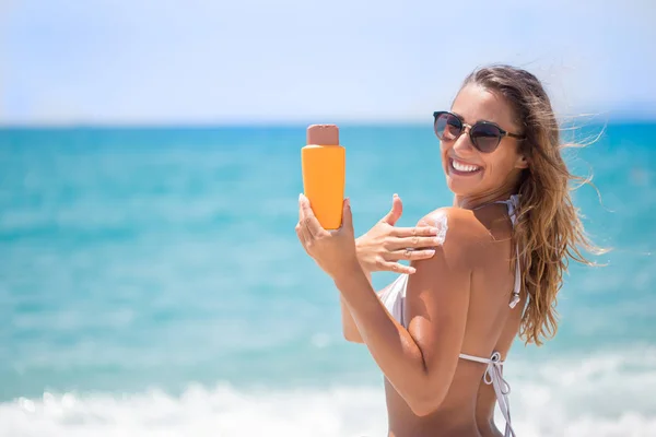 Schöne Mädchen im Bikini Sonnencreme am Strand auftragen — Stockfoto