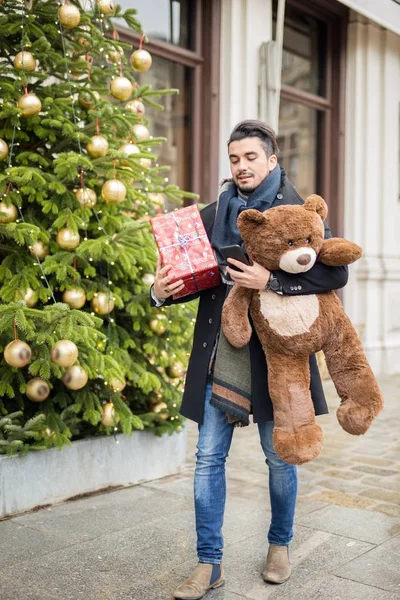 Knappe man lopen op straat voor Kerstmis met een teddy worden — Stockfoto