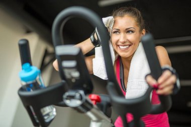 Sabit bir bisiklet üzerinde kardiyo yaparak güzel genç kadın