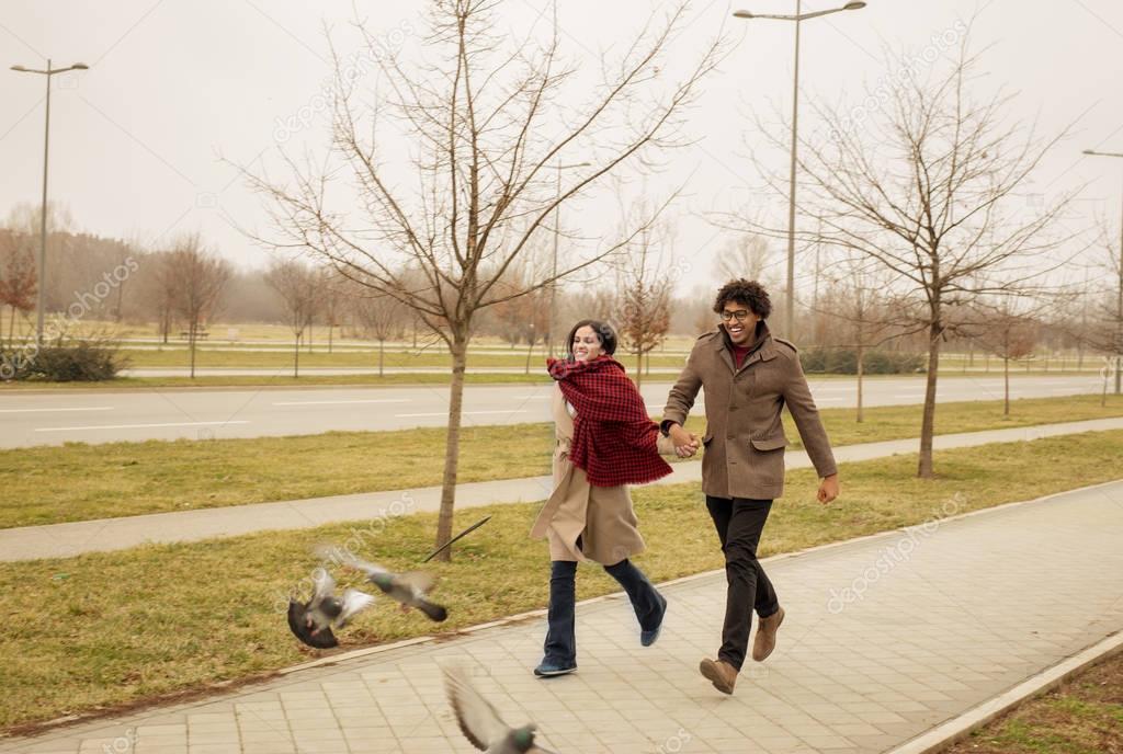 Happy couple running and chasing pigeons