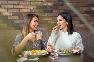 İki kız arkadaşım birbirine bakarak bir restoranda yemek yiyorsunuz.
