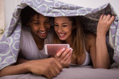 Telefon desteği altında yatakta ile gülümseyen süre iskambil güzel mutlu çift