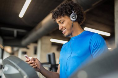 Afro-Amerikan yakışıklı spor salonunda müzik ve gülümseyen süre çalışma dışarı