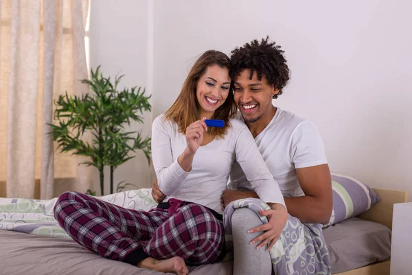 Happy couple with positive pregnancy test focus on test