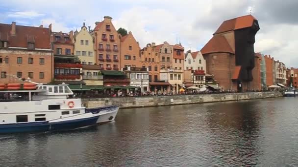 Barco pasando por casas ribereñas junto al río Motlawa en Gdansk, Polonia. Grúa medieval en el fondo . — Vídeos de Stock
