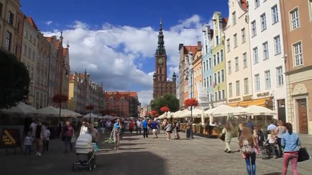 Ludzie spacerują ulicą Długa Długa Długa w Gdańsku. Widoczna wieża ratusza — Wideo stockowe