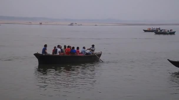 Malá loď přepravující místní obyvatele v blízkosti Ghats nábřeží schodiště vedoucí na břehy řeky Ganges ve Varanasi, Indie — Stock video