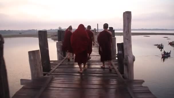 Budist keşişler Mandalay, Myanmar yakınlarındaki Amarapura 'daki Taungthaman Gölü üzerindeki U Bein köprüsünü geçiyorlar. — Stok video
