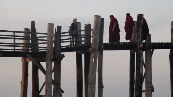 Budist keşişler Mandalay, Myanmar yakınlarındaki Amarapura 'daki Taungthaman Gölü üzerindeki U Bein köprüsünü geçiyorlar. — Stok video