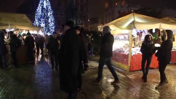 Stalles de marché de Noël sur la place médiévale Rynek Glowny avec la basilique St. Marys à Cracovie, Pologne Séquence Vidéo