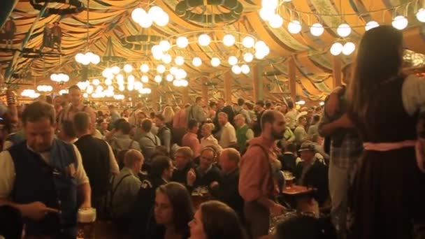 Mensen drinken bier in een van de tenten van het Oktoberfest in München. — Stockvideo