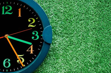 Plastik yapay yeşil çimenlerin üzerinde saat
