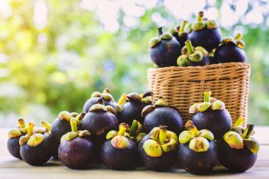 Mangosten meyve sepeti bulanık yeşil arka plana sahip ahşap masa üzerinde