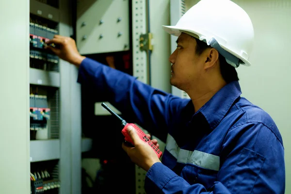 Engineer using walkie-talkie and turning on switch in the electrical cabinet at control room with selective focus