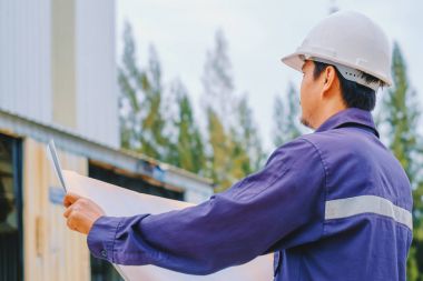 Proje planı inşaat açık site arka plan, endüstriyel kavramı holding beyaz kask ile mühendis